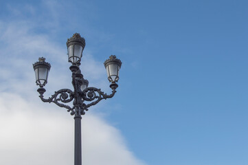 Fototapeta na wymiar A Fernandina-style lamppost on blue sky in a park in Madrid. Spain