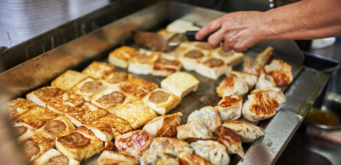 Woman hand reaching for a deep fried spring roll at food truck. Close up of food truck salesman serving street to customer. Asian street food , catering service.