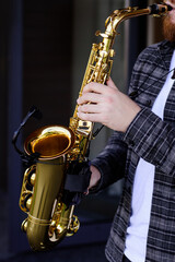 Fototapeta na wymiar Hands of young musician man plays on saxophone 