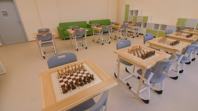 Sets of chessmen on tables with chairs in light spacious classroom at contemporary educative center for children