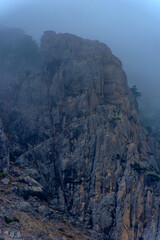 Stony slopes of mountain in dense fog.