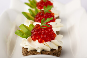 Close-up of an elegant canapé topped with luscious red caviar, accented with fresh green avocado...