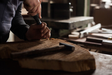 Fototapeta na wymiar Young male carpenter drilling holes in wood in his workshop