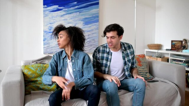 Quarrel, disagreement between a multiracial young couple. Annoyed dissenting guy and girl emotionally sort out the relationship, the guy yells at the girl, the girl resentful turned away from him