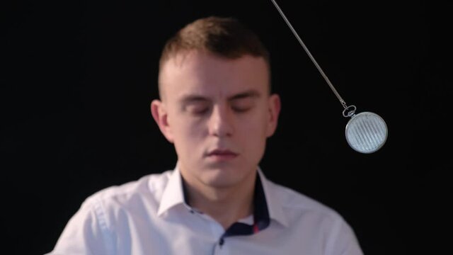 Hypnosis session. A man enters hypnosis while watching a swinging pendulum