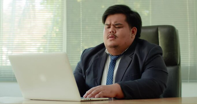 Asian business man which has a fat figure and funny personality, wearing a suit like an executive or a manager using a laptop in the office  . The next time he pondered and thought hard.