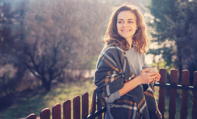 Happy cheerful beautiful curly young woman enjoying morning coffee and nature view on the terrace...
