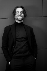 Portrait of overjoyed male in stylish suit, smiling with his eyes closed, posing at the photoshoot. Handsome businessman in fashion cloth happy about well done work of his project, success concept 