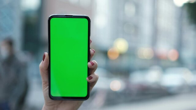 Point of View of voman at street Using Phone With Green Mock-up Screen Chroma Key Surfing Internet Watching Content Videos Blogs Tapping on Center Screen