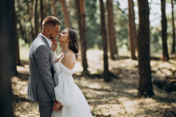 Young wedding couple having photoshoot in forest