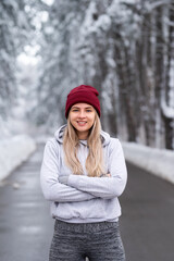 Sportswoman standing in nature on a snowy winter day. Portrait of a beautiful young fitness woman in the snow. 