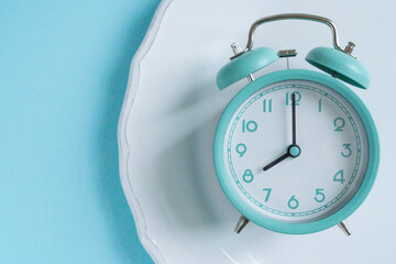 intermittent fasting concept - blue alarm clock, top view