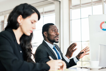 African businessman shares his opinion at a business group meeting, Discussion about last year's review and a new business plan in the office. Businesspeople of various nationalities.