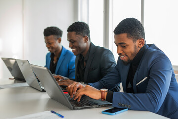 portrait of successful african men in suits working at the table with laptops 