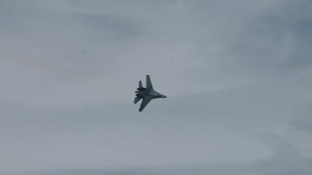 Pilot Su-27 universal all-season fighter pilot performs an inverted flight. After performing  inverted flight aircraft makes left turn against blue cloudy sky. Zhukovsky, Russia, August 19, 2011.
