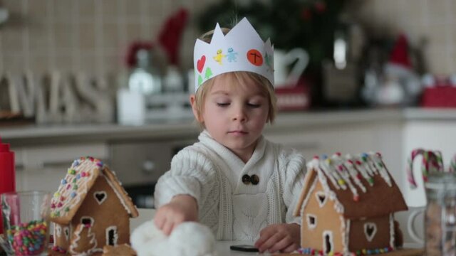 Blond toddler child, cute boy, making Christmas ginger bread house at home