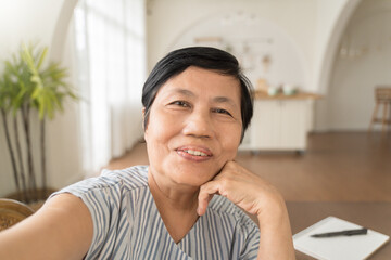 Happy smiling Asian senior woman using mobile phone taking selfie, Grandmother making video call on smatphone.