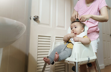 Asian Little baby having haircut with his mother in bathroom
