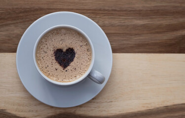 a mug of coffee with a heart on a wooden table