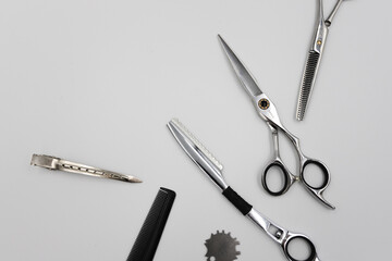 a set of professional combs, scissors, razors and hairpins unfolds on a light background