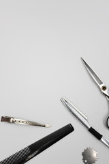 a set of professional combs, scissors, razors and hairpins unfolds on a light background