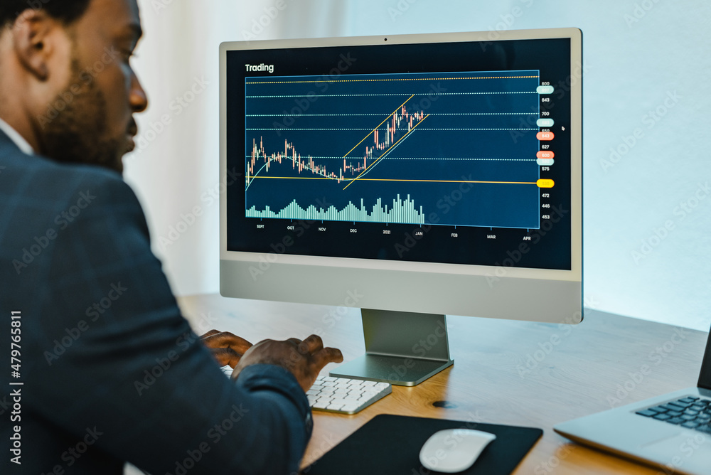 Wall mural Black man analyzing financial diagrams on binary option