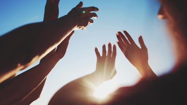 group of cheerful people together party pulling hands to the sun on the beach. teamwork. silhouette people party dancing recreation fun holiday. people music. pull their hands up. religion concept