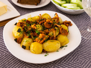 baked potatoes with chanterelles, served with herbs on white plate