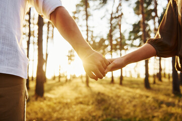 Close up view of hands. Happy couple is outdoors in the forest at daytime