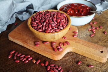 Raw and canned red kidney chilli beans in bowl on a rustic wooden table