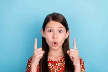 Photo of young astonished girl indicate fingers empty space advertise promotion isolated over blue...