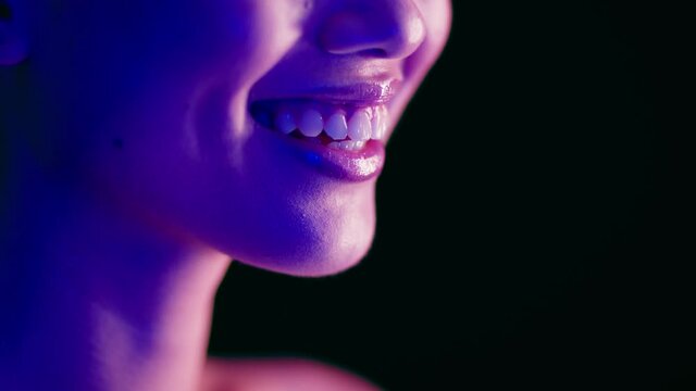 Closeup Shot Of Young Woman's Smile Illuminated With Colorful Neon Light