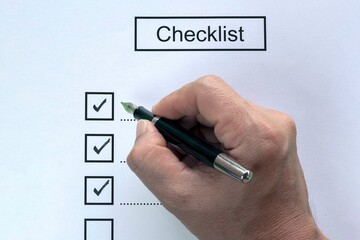 Person checkbox with black pen on checklist form.