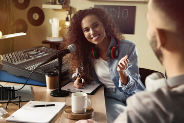 Young African American woman interviewing man in modern radio studio