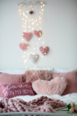 Love sign and valentine decorated bed with pillows, hearts and lights