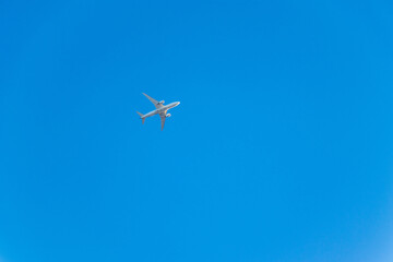 Fototapeta na wymiar 真っ青な空を飛ぶ白い飛行機
