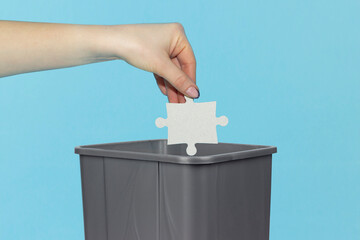 throw puzzle piece into trash can, puzzle in hand in front of trash can, bad idea concept