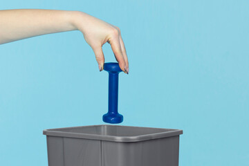 throw fitness dumbbell in trash can, fitness dumbbell in hand in front of trash can, end workout...
