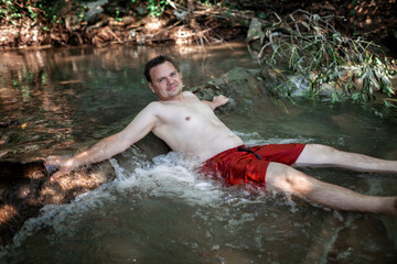Middle aged man bathing in stream canyon river in the mountains, nature pool. Cold water, hardening and natural spa procedure, wildlife and green tourism, active healthy lifestyle, summertime
