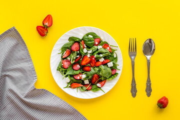 Green spinach salad with red strawberry and goat cheese, top view