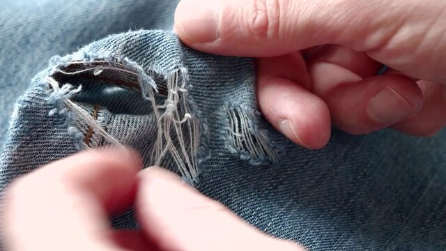 Man explore hole in ripped jeans before sew up it. Close-up of video 4k resolution