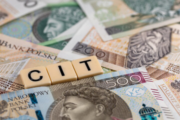 The wording "CIT" translated as Company Income Tax" plus many Polish banknotes. New tax rules in Poland at 2022. Photo taken under artificial, soft light