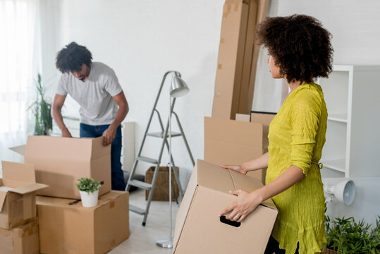 Happy playful African American couple moving in a new apartment, unpacking, moving stuff, purchase and rent property, investment concept