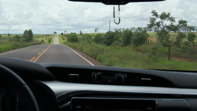 Driving on the road with no traffic, background for car travel or safe driving. View from the front window to the road. Rural areas landscape of Mato Grosso do Sul state, Brazil.