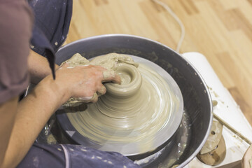 Fototapeta premium Pottery workshop. Closeup of woman artist hands molding clay on pottery wheel. Creative handmade craft. Ceramic studio.