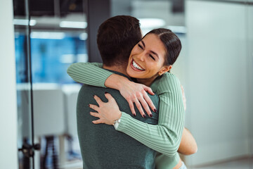 Smiling caucasian woman, wraping her arms around her male business partner.