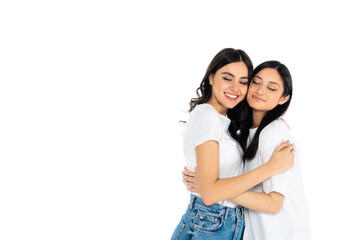 Naklejka premium pleased interracial women in t-shirts embracing with closed eyes isolated on white.