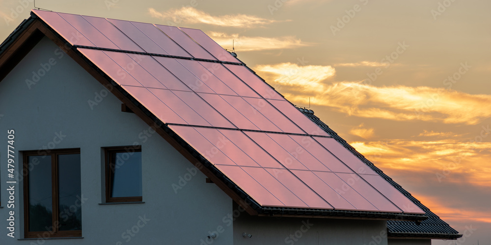 Wall mural photovoltaic panels on the roof of the house during a beautiful sunset