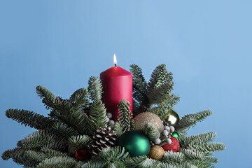 Hand-decorated lighting candle with dry cones, spruce twigs , golden, red balls  on a blue background. Eco DIY concept for New Year and Christmas.