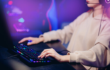 Professional cyber video gamer woman hand studio room with personal computer armchair, keyboard for stream in neon color blur background banner